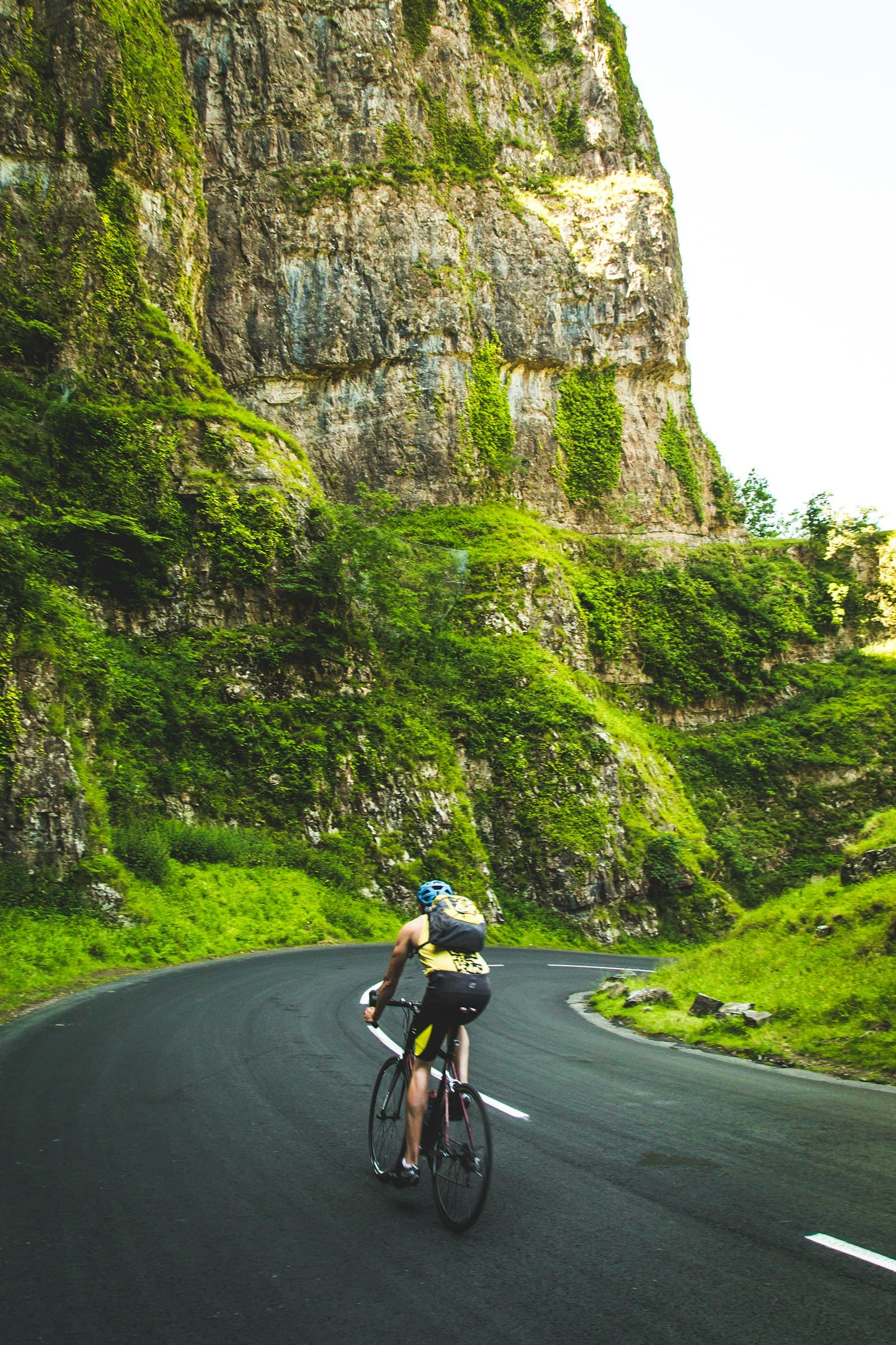A cyclist under a green cliff