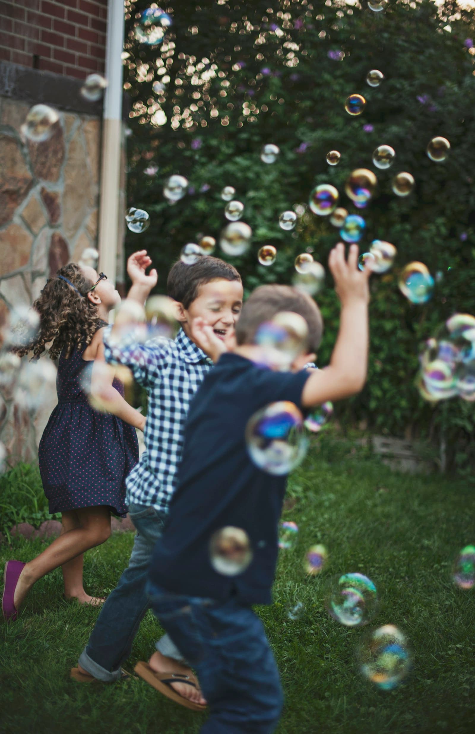 Children chasing bubbles in a garden