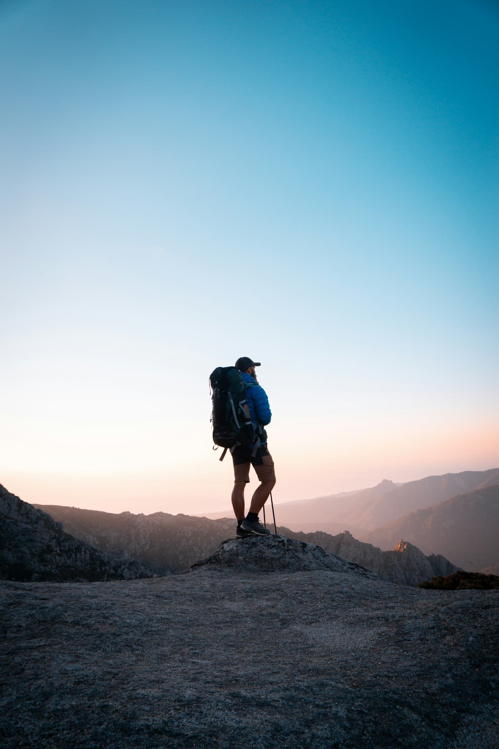 A hiker on a rocky peak at golden hour
