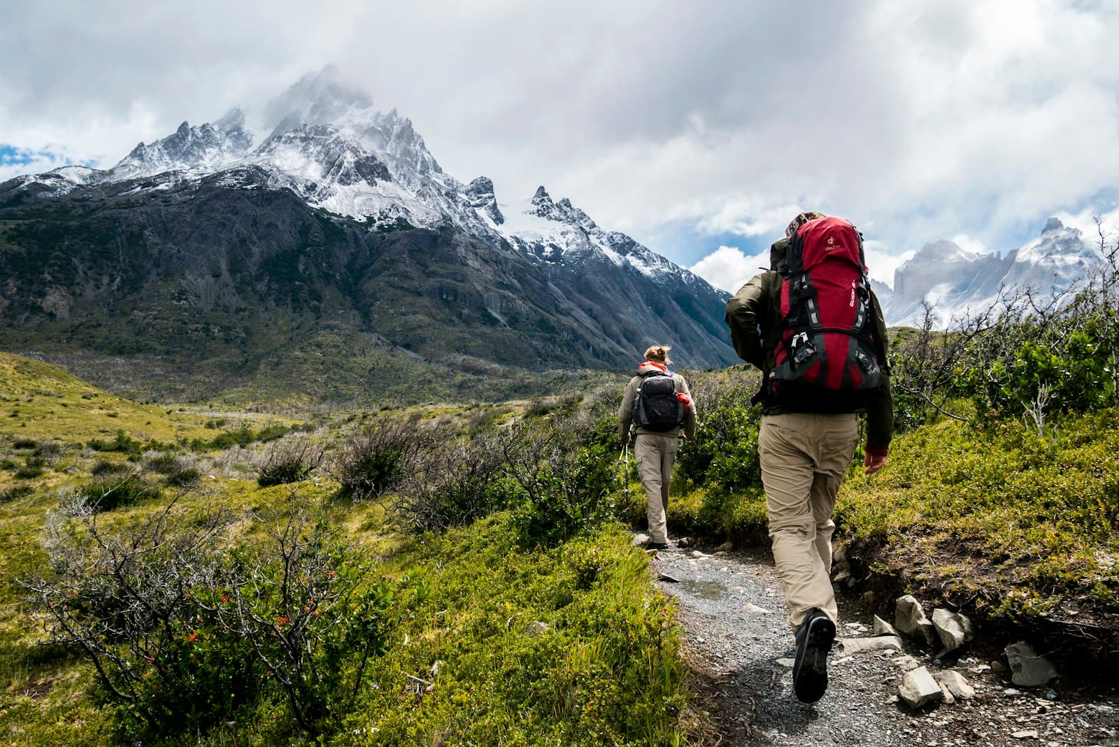 Hikers walking towards snowy mountains