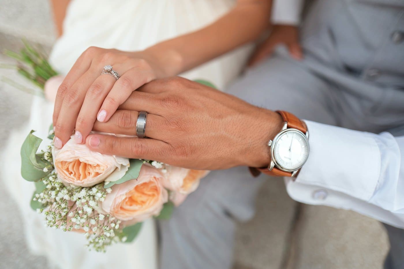 Hands with wedding rings over a bouquet